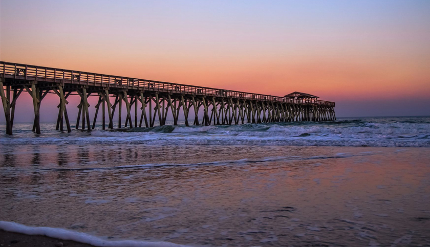 Myrtle Beach State Park pier jutting into the Atlantic Ocean with a sunset